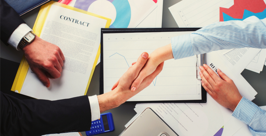 Man and woman shaking hands over table with financial graphics (1)