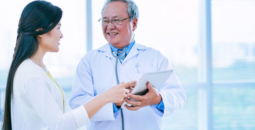Young woman and her doctor discussing information on tablet computer
