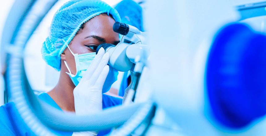 Young Black female ophthalmologist looking through surgical microscope before starting laser correction surgery